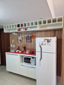 a kitchen with a white refrigerator and a microwave at Apt - Orla de Maceio in Maceió