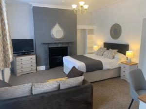 1 dormitorio con cama, sofá y TV en Abbots Mead Hotel, en Shrewsbury