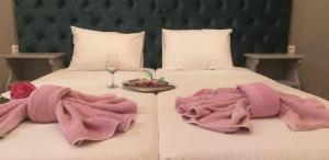 two beds with pink towels and a glass of wine at Kapetanios Boutique in Agios Georgios