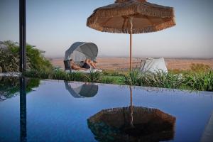 een persoon naast een zwembad met een parasol bij Y HOUSE SUITES in Mishmār Hāyardin