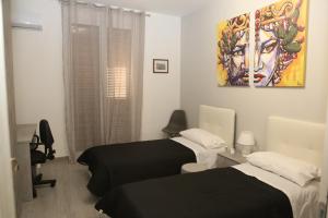 Habitación con 2 camas y una pintura en la pared. en Camurría Sicily home, en Montelepre