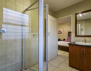 a bathroom with a shower and a sink and a bedroom at Studio Apartment in Hatfield in Pretoria