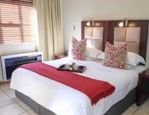 a bedroom with a large white bed with a red blanket at Studio Apartment in Hatfield in Pretoria