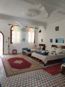 a large bedroom with two beds and a red rug at Riad dar Ahlam in Aït Baha