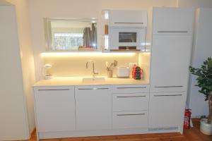 a kitchen with white cabinets and a sink at LUXOMES: Design Apartment - Near Airport in Nürnberg