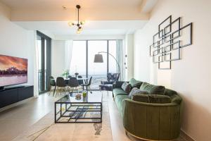 a living room with a green couch and a table at Stylish 1 Bedroom in 5242 by Ofex in Dubai
