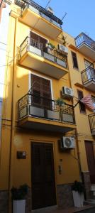 een hoog geel gebouw met balkons en een deur bij Camurría Sicily home in Montelepre