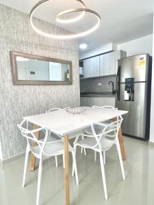 una cucina con tavolo e sedie bianchi e frigorifero di Apartamento amoblado cerca al aeropuerto a Pereira