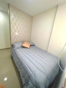 a bed in a bedroom with a blue comforter at Apartamento amoblado cerca al aeropuerto in Pereira