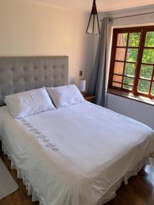 - une chambre avec un lit blanc et une fenêtre dans l'établissement Departamento Pucón, à Pucón