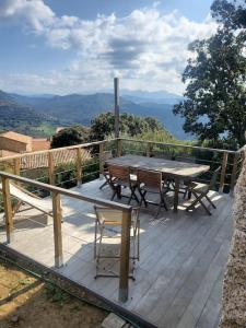 drewniany taras ze stołem i krzesłami w obiekcie Meublé de tourisme avec terrasse vue montagne w mieście Grossa