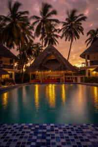 una piscina frente a un complejo con palmeras en Kupaga Villas Boutique Hotel - Adults Only en Jambiani