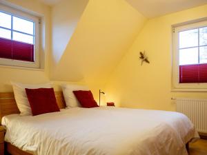 a bedroom with a white bed with two windows at Villa Arielle, FW 5 in Zingst