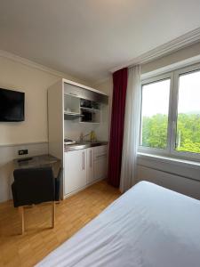 a hotel room with a bed and a desk and a window at Swiss Star Irchel - Self Check-In in Zürich