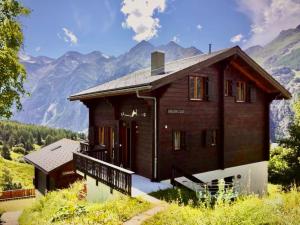 a wooden house with mountains in the background at Chalet Arabesque - Switzerland in Grächen