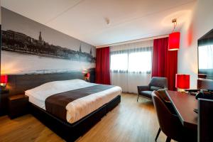 um quarto de hotel com uma cama grande e uma secretária em Bastion Hotel Almere em Almere