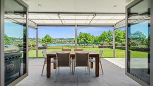 ein Esszimmer mit einem Tisch und Stühlen sowie einem großen Fenster in der Unterkunft The Lakehouse - Tauranga Holiday Home in Tauranga