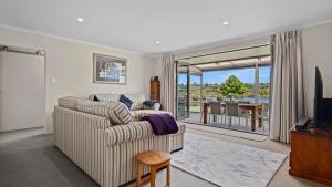 ein Wohnzimmer mit einem Sofa, einem TV und einem Balkon in der Unterkunft The Lakehouse - Tauranga Holiday Home in Tauranga