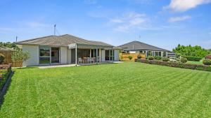 a house with a large lawn in front of it at The Lakehouse - Tauranga Holiday Home in Tauranga