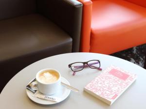 a cup of coffee and a book on a table at Hotel Poseidon Playa in Benidorm