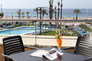 a table with a drink on it with a view of the beach at Hotel Poseidon Playa in Benidorm