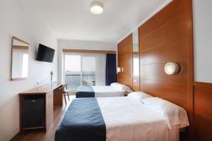 a hotel room with two beds and a desk at Hotel Poseidon Playa in Benidorm