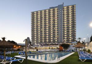 a hotel with a swimming pool and chairs and a building at Hotel Poseidon Playa in Benidorm