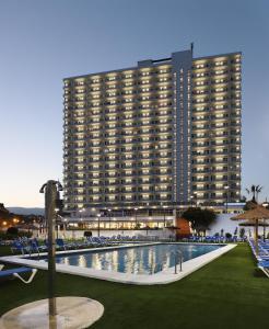 a large building with a swimming pool in front of a building at Hotel Poseidon Playa in Benidorm