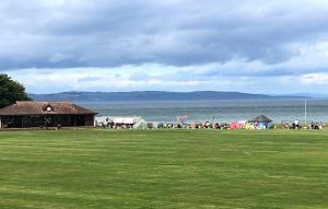 a group of people standing in a field near the water at Amazing views across the Moray Firth, Private Suntrap Patio, 300m from the Beach, off street parking! in Nairn +16 photos