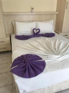 a bed with purple and white sheets and pillows at Kahraman Hotel in Side