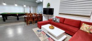 a living room with a red couch and a pool table at YasmeN suite in Mas'ada