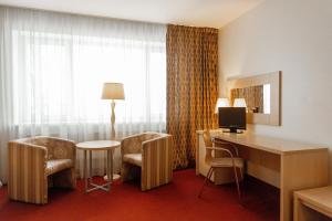 a hotel room with a desk and chairs and a television at Rixwell Segevold Hotel in Sigulda