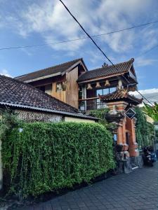 a house with a hedge in front of a building at Sunshine Vintage House in Ubud