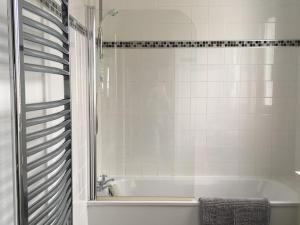 a white bathroom with a tub and a shower at Amazing views across the Moray Firth, Private Suntrap Patio, 300m from the Beach, off street parking! in Nairn