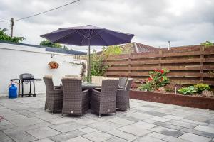a table and chairs with an umbrella on a patio at Amazing views across the Moray Firth, Private Suntrap Patio, 300m from the Beach, off street parking! in Nairn