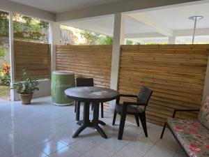 a patio with a table and chairs and a fence at Studio cosy avec piscine in Saint-Joseph