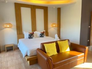 Wangpruksa Resort في مواكليك: غرفة نوم بسرير واريكة جلدية