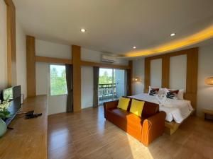 Wangpruksa Resort في مواكليك: غرفة نوم كبيرة مع سرير وأريكة
