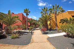 chodnik z palmami i budynek w obiekcie Oasis Tamarindo sport e relax w Corralejo