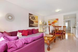 salon z fioletową kanapą i stołem w obiekcie Oasis Tamarindo sport e relax w Corralejo