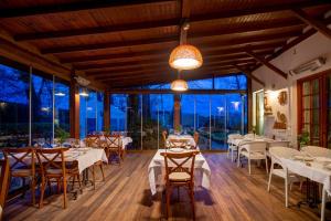 un restaurante con mesas, sillas y ventanas grandes en Beta Home Lake House Sapanca, en Sapanca