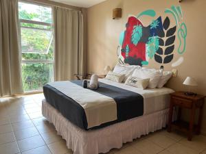 ein Schlafzimmer mit einem großen Bett und einem Gemälde an der Wand in der Unterkunft Beer Hotel Iguazú in Puerto Iguazú