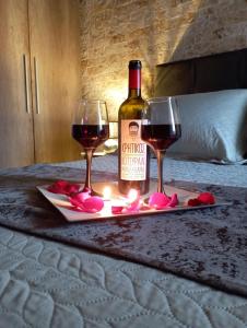 Una botella de vino y dos copas de vino en una cama. en Harmony, en Lávrion