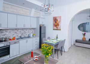 une cuisine avec des placards blancs et une table ornée de fleurs jaunes dans l'établissement Villa Vasso Sea View Residences, à Agnítsini