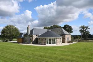 a large stone house with a grass field at Laverockbank Steading in Buchanty