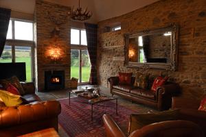 a living room with leather furniture and a stone wall at Laverockbank Steading in Buchanty