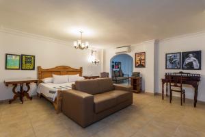 a bedroom with a bed and a couch and a desk at Hotel Kartaxa in Cartagena de Indias