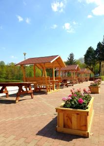 un grupo de mesas de picnic y bancos con flores en Złoty Potok Resort, en Złoty Potok