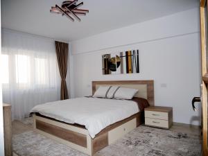 una camera da letto con un letto con lenzuola bianche e una finestra di Apartament David a Câmpulung Moldovenesc