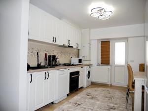 una cucina con armadietti bianchi e lavastoviglie nera di Apartament David a Câmpulung Moldovenesc